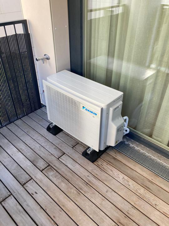 Daikin Außengerät auf einem Holzbalkon, auf Schwingungsdämpfern