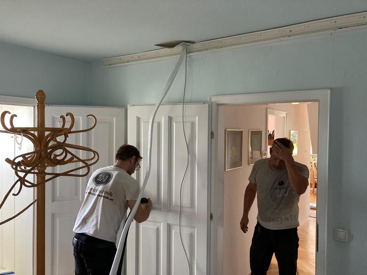 Zwei Monteure ziehen Leitungen in einer Altbauwohnung ein