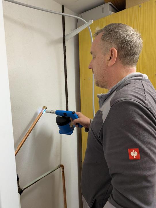 Monteur lötet eine Kupferleitung mit dem Brenner